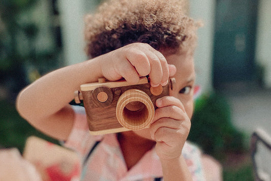 Child taking a pretend photo with the walnut wooden toy camera