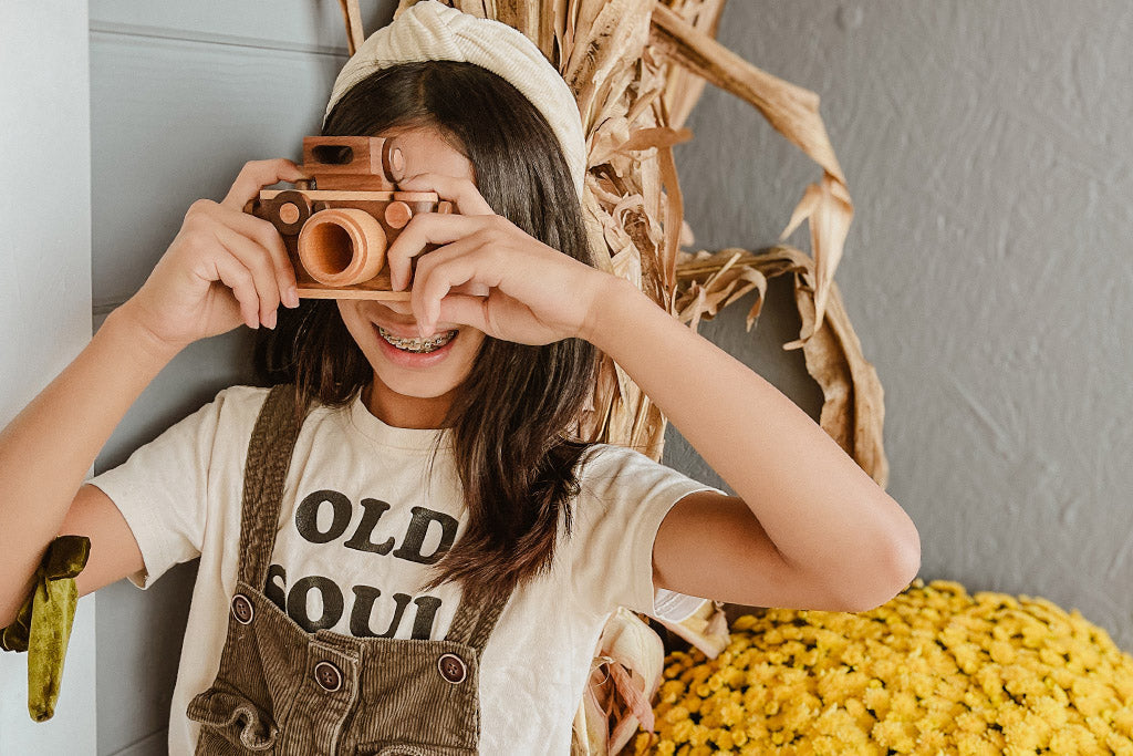 Girl playing with the vintage style wooden toy camera