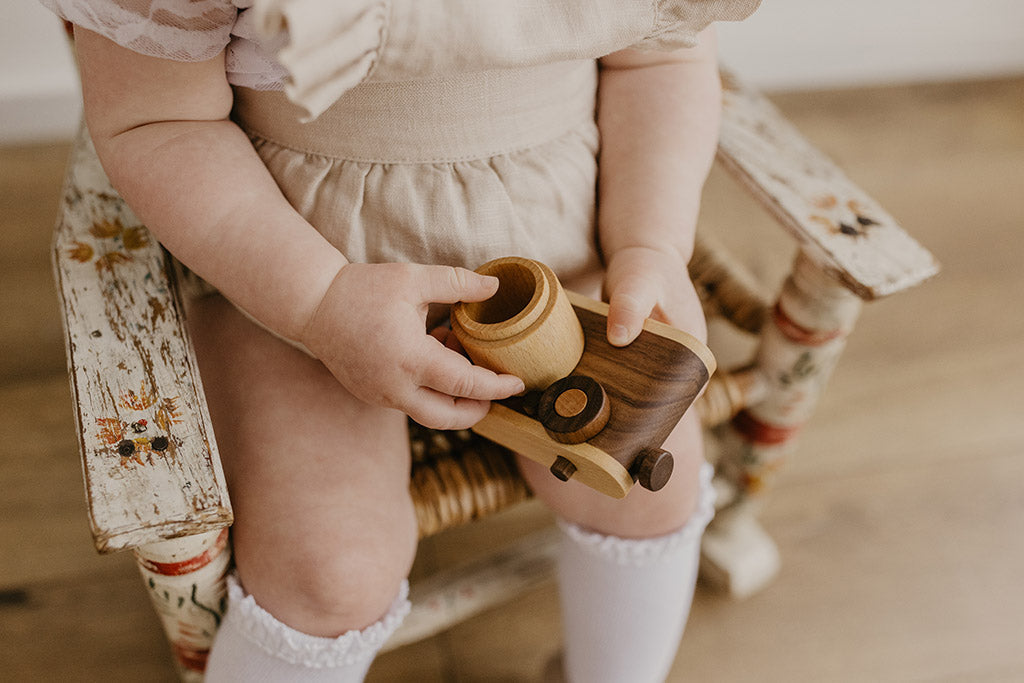 Child holding the walnut wooden toy camera in her lap
